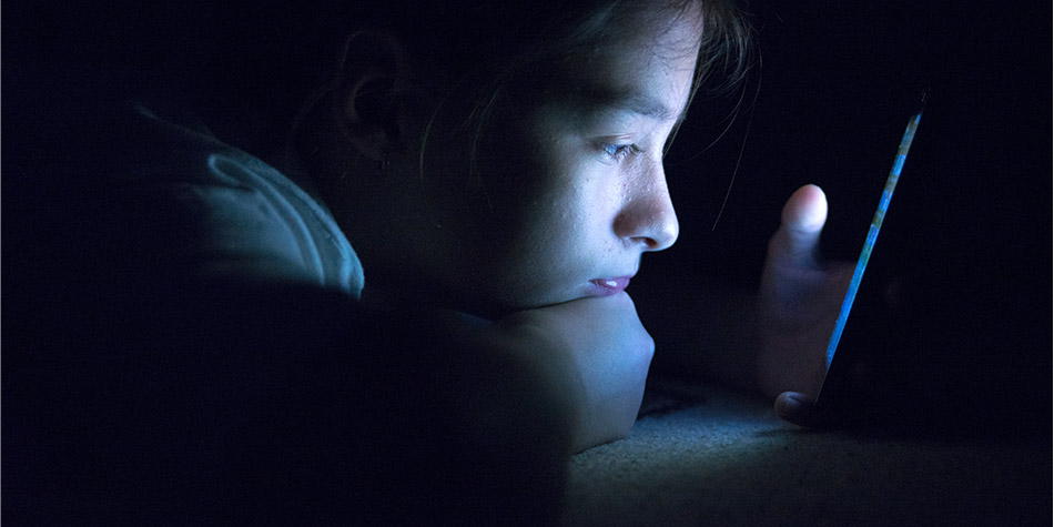 a child looks at a cellphone late at night